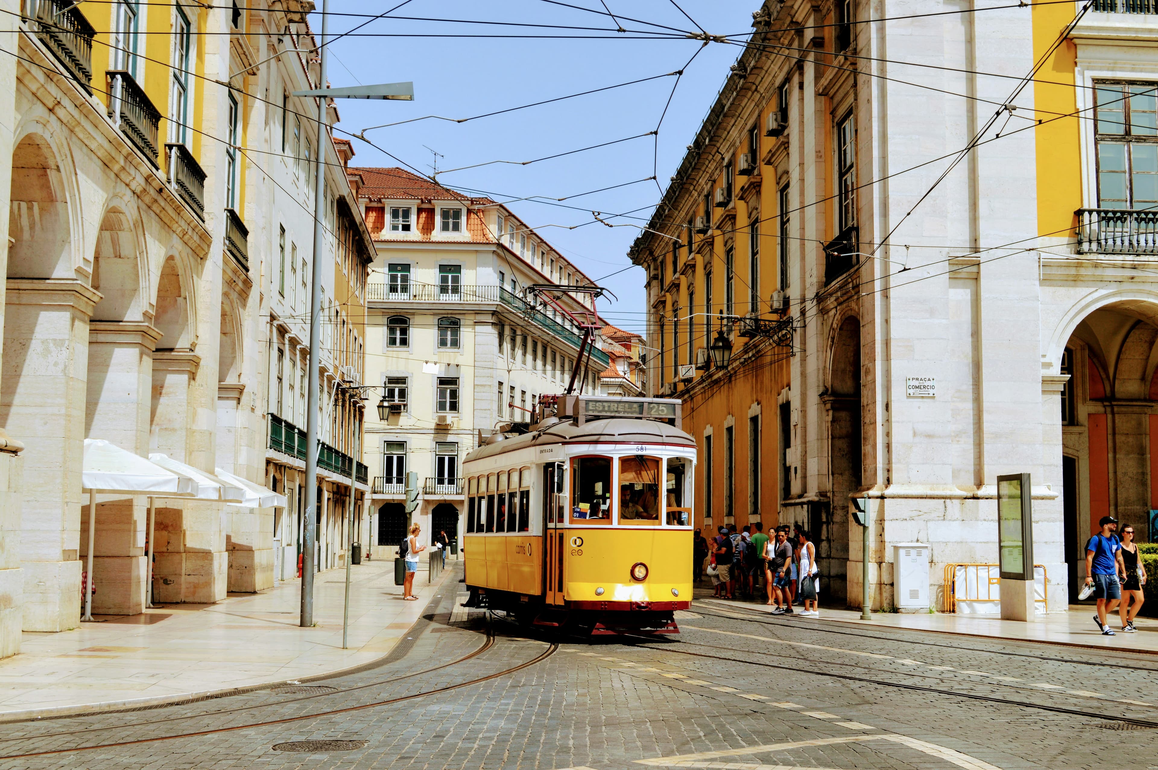 Yellow tram travelling through central Lisbon